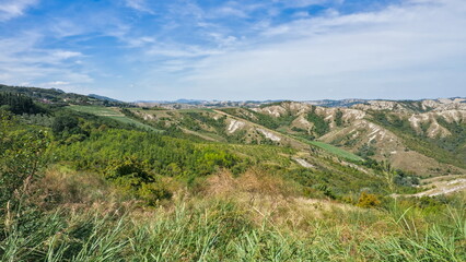 A panoramic view of the rugged, eroded hills and clay slopes (calanchi) of the badlands landscape in the Apennine foothills of Emilia-Romagna, Italy.