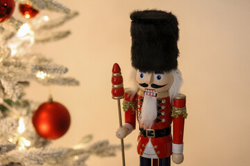 A decorative nutcracker figure displayed near a Christmas tree with warm white lights and ornaments.