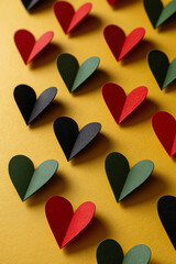 Juneteenth-inspired vertical sequence of red, green, and black hearts arranged against a bright yellow surface