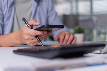 Close up businessman hands holding pen smartphone calculator foreground. Financial accountant checking data budget tax investment office business concept.