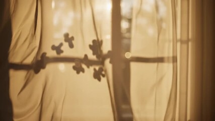 A soft-focus sepia-toned view of a sheer curtain with a dark floral pattern backlit by warm sunlight streaming through a window - Powered by Adobe