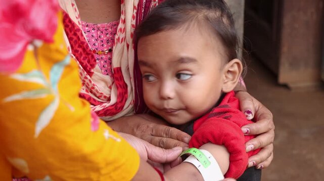 Screening a baby for malnutrition with MUAC tape in a rural Nepal village, ideal for projects focused on global health and child survival programs
