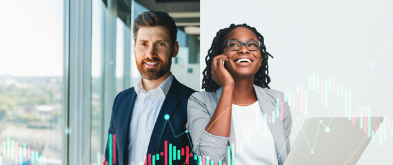 Two business professionals stand in a sleek office space. A man in a suit and a woman in a blazer smile and engage in conversation while using technology. City skyline is visible outside.