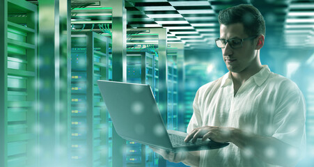 Data center technician monitors server performance with a laptop, ensuring stable network operations, system security, and efficient infrastructure management.