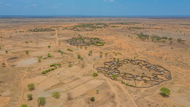 Aerial view of the Manyatta Villages, circular clusters of thatched huts encircled by rough stone walls, stand as resilient outposts against the arid landscape, Karamoja, Northern Region, Uganda.