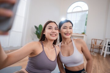 Friends take a selfie in a bright indoor space during their workout session while enjoying their...