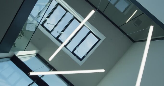 Upward roll shot of contemporary lights and glass skylight in a stylish office building. Minimalist design, innovative lighting and modern workspace character.
