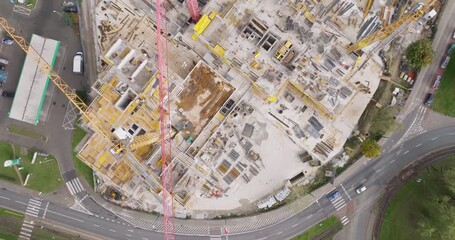 Direct aerial drone shot over active housing construction. Materials, cranes and workers illustrate the Polish and European residential market’s dynamic growth and industry standards.