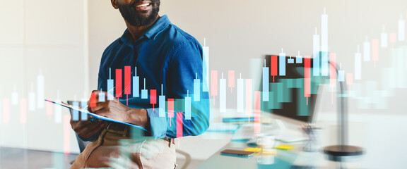 A business person reviews graphical data trends on a digital interface inside a bright office. The individual smiles while jotting down notes, showcasing a productive work environment.