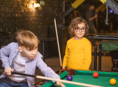 A cheerful young girl and teenager boy plays pool billiards - Powered by Adobe
