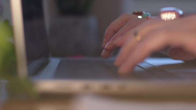 A woman's hands typing on a laptop keyboard in an office, doing copywriting, writing articles, or creating stories for social media. A close-up of a computer keyboard and a person typing. 
