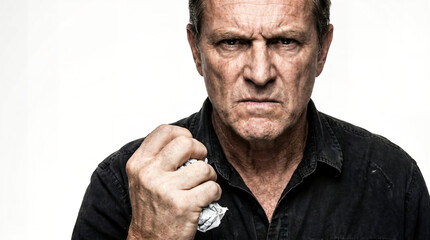 Angry man with an intense expression clenching his fist and holding crumpled paper against a white background.