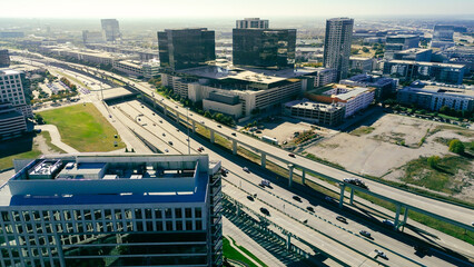Rooftop HVAC units at modern office buildings mirrored glass border major highway 121 corridor, flanked by structured parking corporate, retails zones in dense metropolitan setting, Plano, Texas