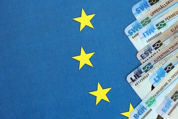 Permanent resident or residence permit cards lies on European Union flag. Paper specimen cards close up
