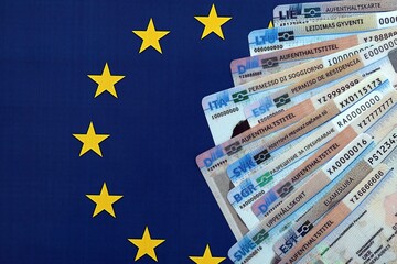 Permanent resident or residence permit cards lies on European Union flag. Specimen cards close up