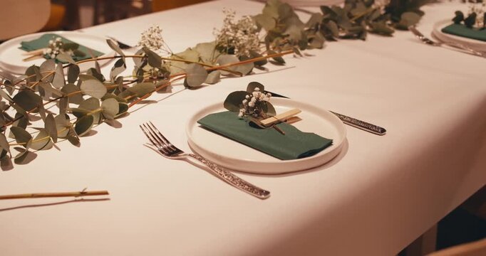 modern elegantly set table in luxurious expensive Michelin restaurant. plates napkins, cutlery and decorations fresh flowers and plants on table. delicate pastel green decoration for dinner atmosphere
