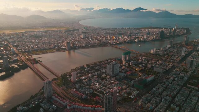 sunset in Vietnamese coastal Da Nang city, Han river and Hai Chau district with bridges, sand beach and My An with skyscraper hotels and resorts, blue sea of Danang, Vietnam, aerial drone view 4k