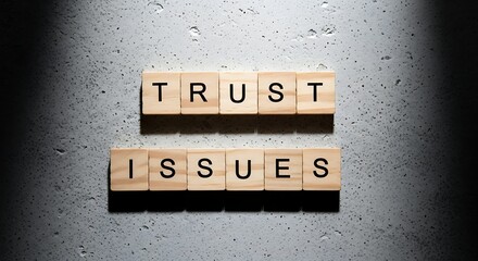 Trust issues" concept with wooden blocks on grey textured surface.