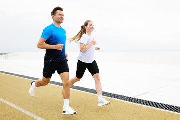 Couple runs together on a track during a workout session