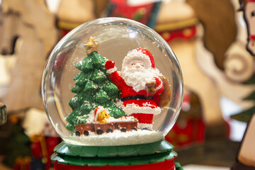 A glass ball with a Santa Claus and Christmas tree figurine inside