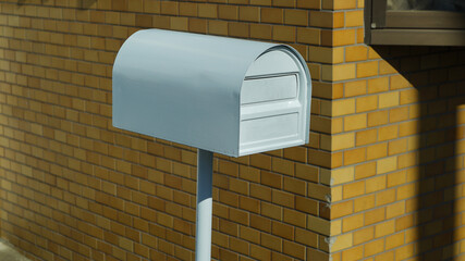 White metal post box standing outdoors, used for collecting mail and letters securely.