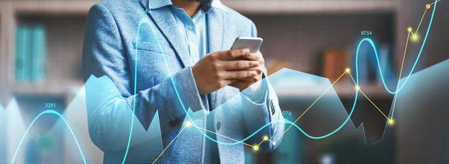 A successful Hindu businessman engages with his cellphone in a sleek office. He utilizes a mobile application for professional communication and managing business tasks effectively.