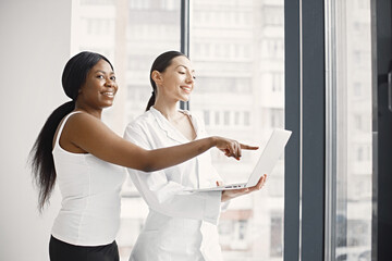 Portrait of female caucasian doctor and black patient standing in office at clinic