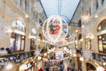 Abstract Christmas bokeh lights and festive decorations inside modern shopping mall with blurred people and glowing holiday atmosphere in winter season