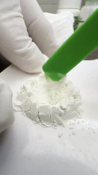 Vertical video social media - Macro closeup in a dental lab of thick specialist liquid inside a raised wall of powder, being mixed together to make cement for a dental procedure.