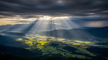 Majestic aerial view of a mountain valley with dramatic crepuscular sun rays shining through stormy clouds, highlighting lush green fields and a meandering river below.
