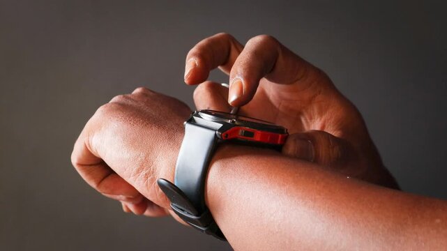 Closeup of Asian man setting alarm on smartwatch before going to bed. Close-up man checking data on smart watch in dark room.