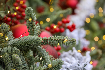 Christmas tree with red toys and festive illumination, golden lights on background. New Year tree with toys