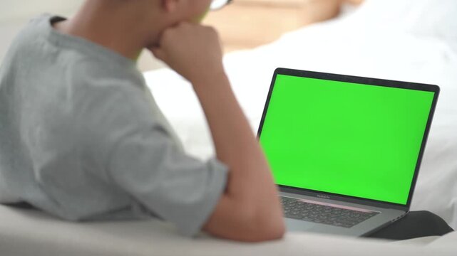 Friends watching laptop with green screen on bed - technology mockup template