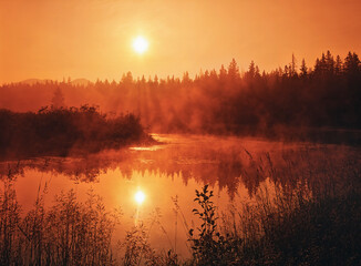 sunrise in the adirondack mountains in a creek near lake placid with reflection of morning fog and brilliant rising sun in orange