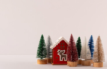 Colorful Christmas decoration trees and a small house on a white background. Happy Christmas decorative idea and holiday concept. Copy space