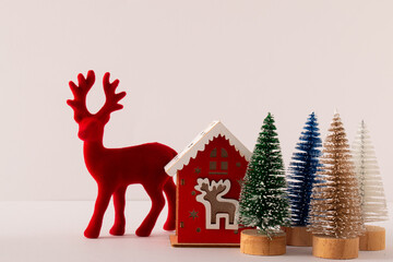 Red Christmas reindeer and a small house on a white background. Happy Christmas idea and holiday concept. Copy space