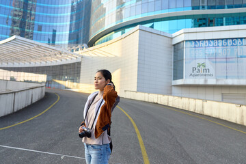 Photographer with camera on a city street amid modern architecture and curved walkways, daylight urban scene, casual outfit, capturing a dynamic outdoor urban landscape