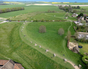 Aerial view of ancient stones standing sentinel on the green landscape near the village, a tranquil scene under the vast sky, Marlborough, England, United Kingdom.