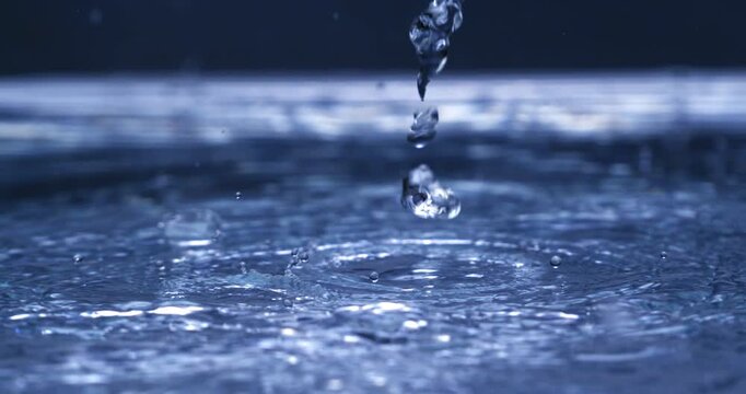A dramatic slow-motion water splash forming rising droplets, captured in cool blue cinematic lighting. Perfect for meditation visuals, backgrounds, and artistic video compositions.