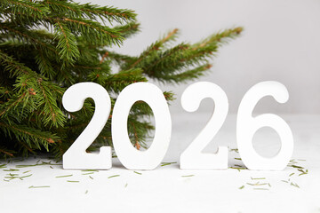 Happy New Year greeting card 2026. Spruce branches, white wooden numbers 2026.