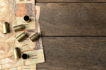 Used old ammunition casings with brazilian real bills with copy space
