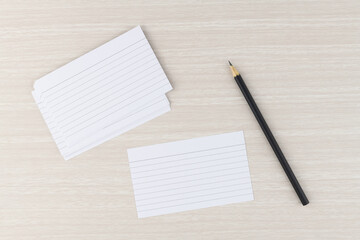 Line index cards with pencil over wooden table