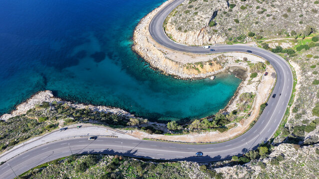 Aerial drone photo of serpent seaside road forming small coves known as "Limanakia" next to famous Asteras Peninsula and lake Vouliagmenis, Athens Riviera, Attica, Greece