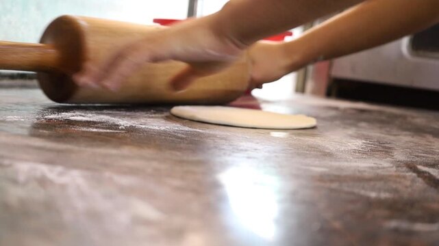 A chef's hands expertly roll out thin, soft dough for fresh shawarma bread. Captures the traditional, hands-on craft of authentic street food.