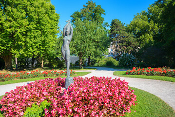 sculpture of female dancer, spa gardens Salzburg. flower bed with begonias and roses