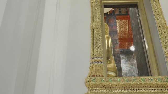 Detailed shot showing the intricate golden patterns and reflection on a traditional Thai temple window.