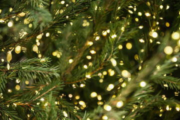 Blurred lights garland at festive Christmas tree and defocused background. Xmas holiday abstract...