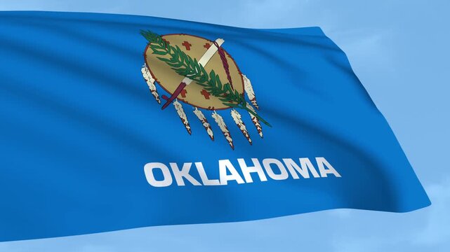 Oklahoma flag is waving against a clear blue sky.