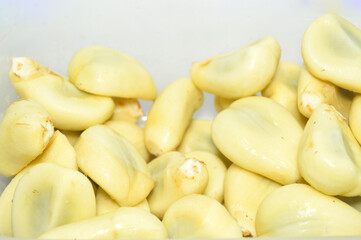 Close-up of peeled, white Salak (Snake Fruit) seeds, ready to eat in a plastic container. Represents fresh tropical fruit, Indonesian cuisine, and natural sweetness.