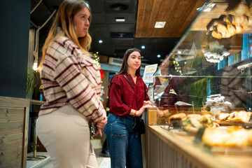 Gen z young women choosing pastries in cafe